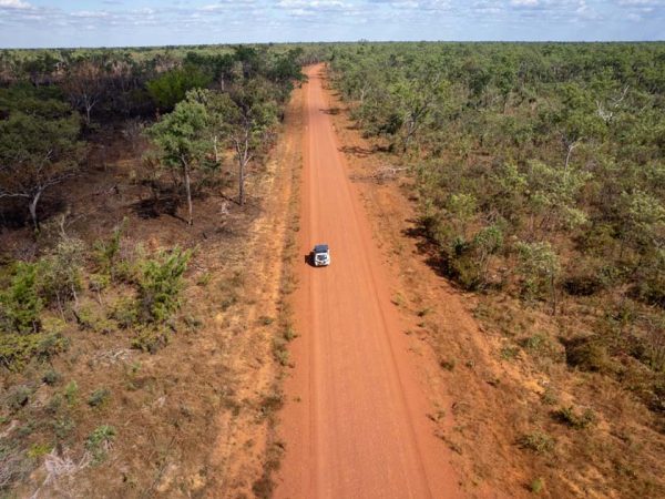 Drohnenaufnahme eines 4WD auf einer Gravel Road die bis zum Horizont führt, in Australien