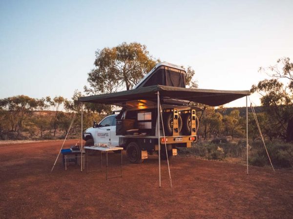 Ein 4WD Geländewagen macht Rast im Outback in Australien. Die Schattenmarkise und das Dachzelt sind aufgebaut im Abendlicht des Sonnenuntergangs