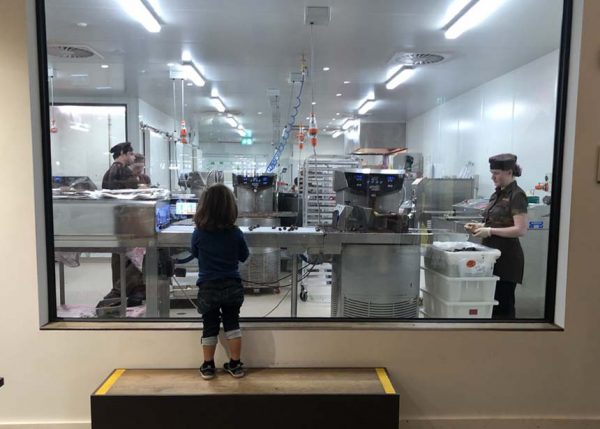 Ein Kind schaut durch eine Scheibe in die Produktionsräume einer Schokoladenfabrik in Australien 