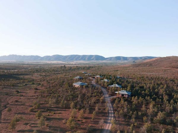 Luxury Eco-villas Rawnsley Park Station am Flinders Ranges Nationalpark/ ©Photo: Tourism Australia / South Australia Tourism Commission Der Flinders Ranges Nationalpark aus der Sicht einer Drohne, mit eine Straße Richtung Bergkette davor.