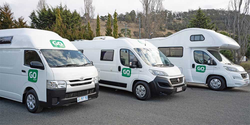 Drei australische Budget-Camper stehen in ihrem Depot auf einem Parkplatz