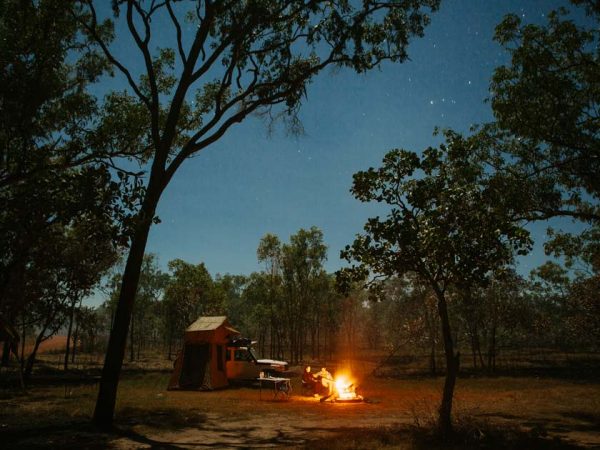 Ein 4WD-Camper auf einer Lichtung im Outback, kurz nachdem die Sonne untergegangen ist. / ©Photo: thl- Apollo Camper Ein 4WD-Camper auf einer Lichtung im Outback, kurz nachdem die Sonne untergegangen ist. Ein Lagefeuer brennt an dem 2 Personen sitzen.