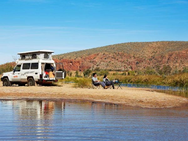 Ein Pärchen macht Rast an einem kleinen Fluss, sitzt auf Campingstühlen und genießt den Ausblick auf eine hüglige Landschaft in Australien./ ©Photo: thl-Apollo Camper Ein Pärchen macht Rast an einem kleinen Fluss, sitzt auf Campingstühlen und genießt den Ausblick auf eine hüglige Landschaft in Australien. Im Hintergrund steht ihr 4WD Geländewagen