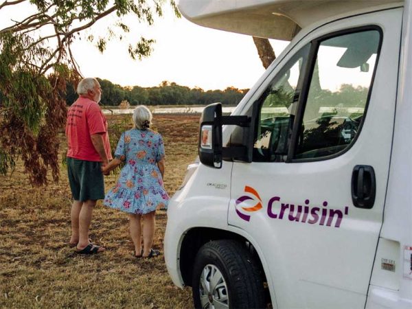 Ein älteres Paar steht neben ihrem Wohnmobil in Australien und schauen über ein Feld in die Ferne/ Photo: © Cruisin Motorhomes Ein älteres Paar steht neben ihrem Wohnmobil in Australien und schauen über ein Feld in die Ferne