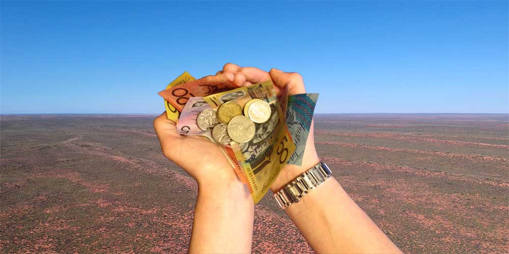 Hände halten australisches Geld über einer australischen Landschaft