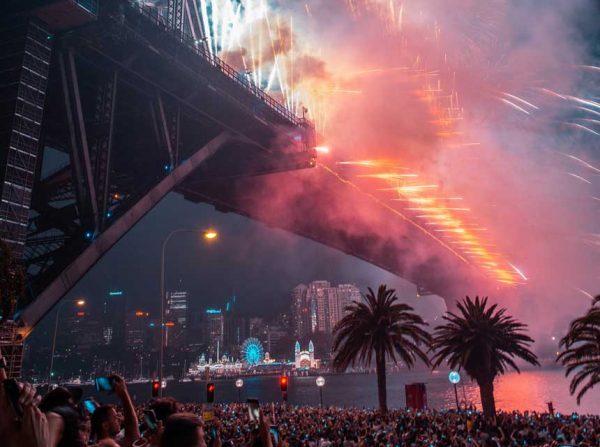 Bild vom Feuerwerk ganz dicht an der Sydney Harbour Bridge am Sylvesterabend in Sydney, Tausende Menschen davor die alles per Handy filmen 