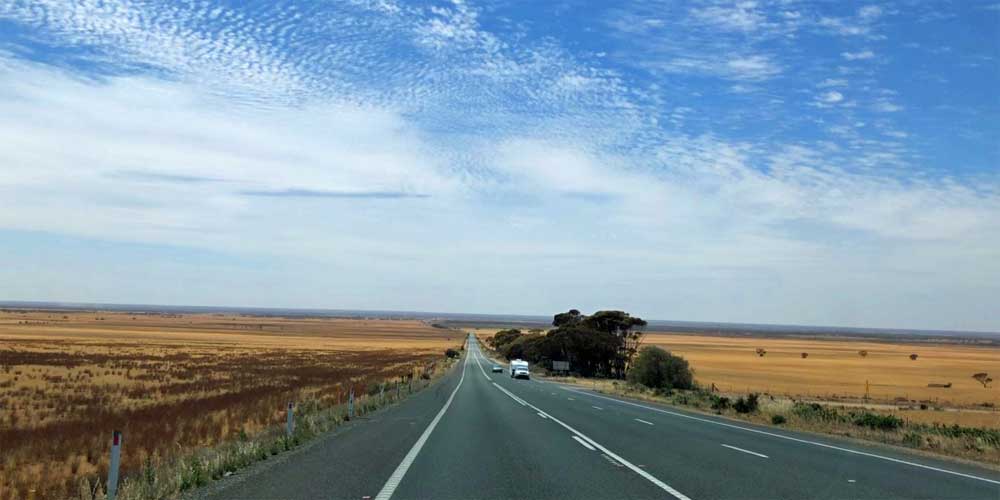 Eine Landstraße in Australien mit Feldern rechts und links.