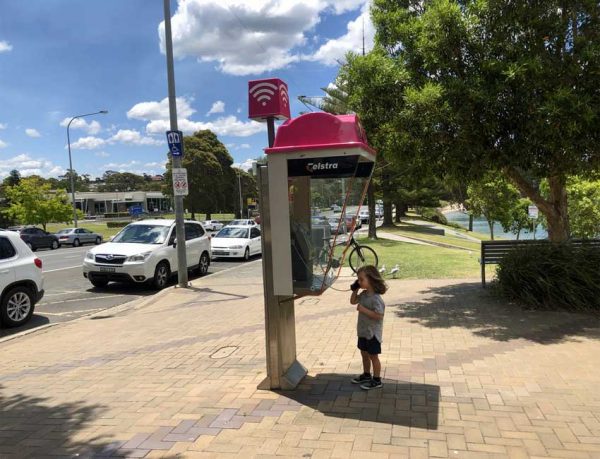 Ein Kind telefoniert an einer öffentlichen Telefonzelle in Australien